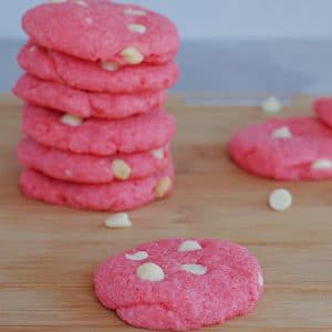 Strawberry milkshake cookie on a cutting board with pile of cookies behind
