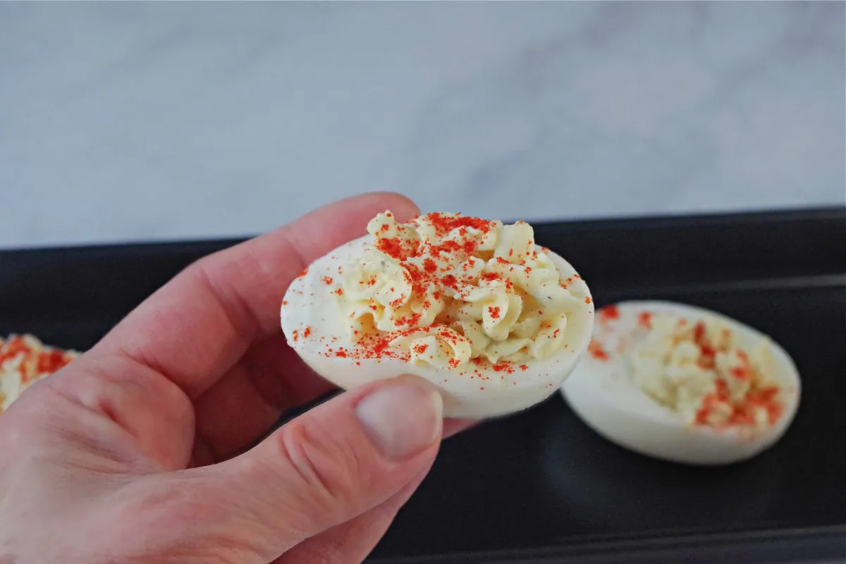 deviled egg being held up between held up between thumb and 2 fingers