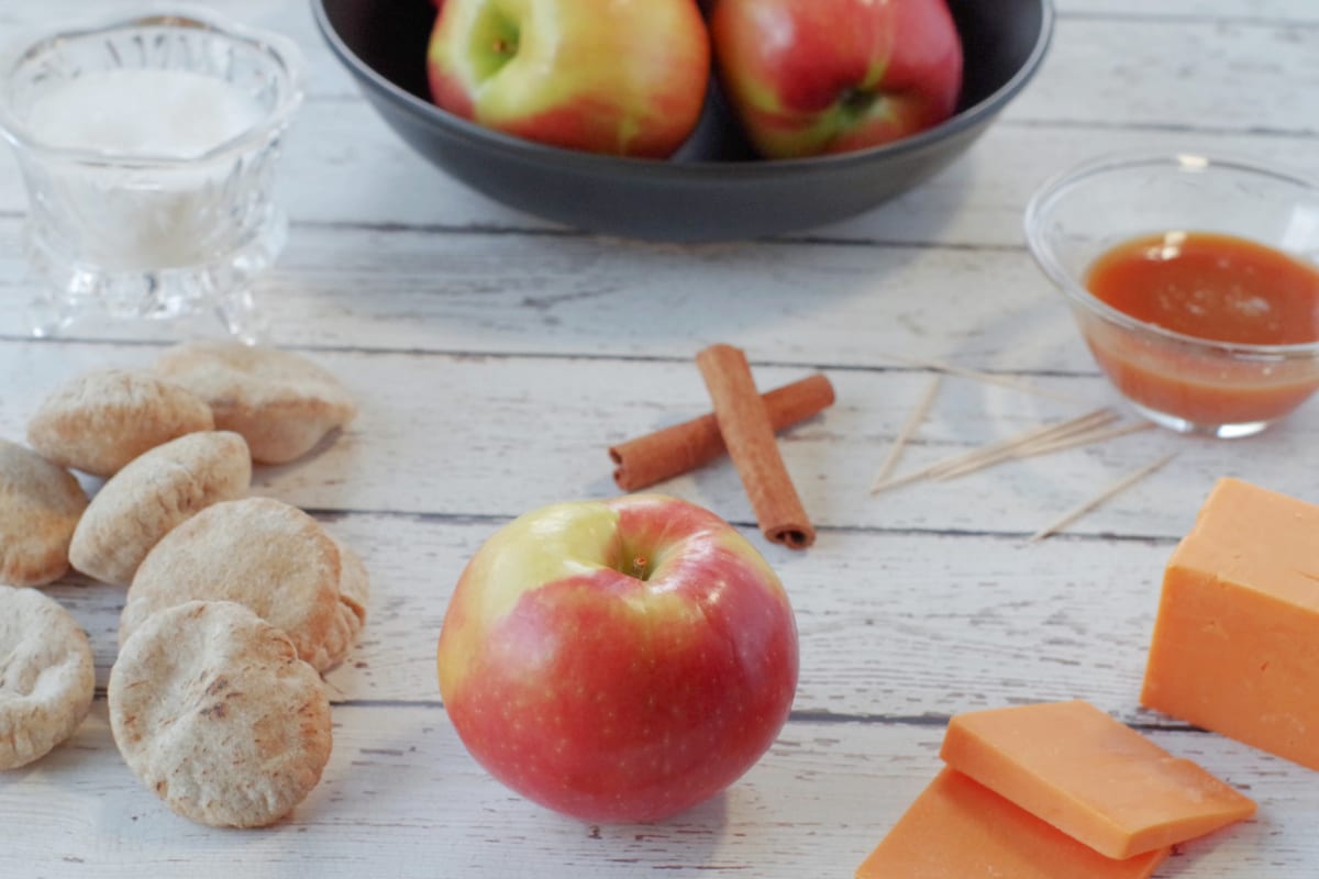 photo of apple pie bites snack ingredients, including apple, mini pitas, cinnamon, caramel and cheese