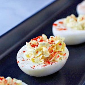 deviled egg with paprika sprinkled on top on black serving tray