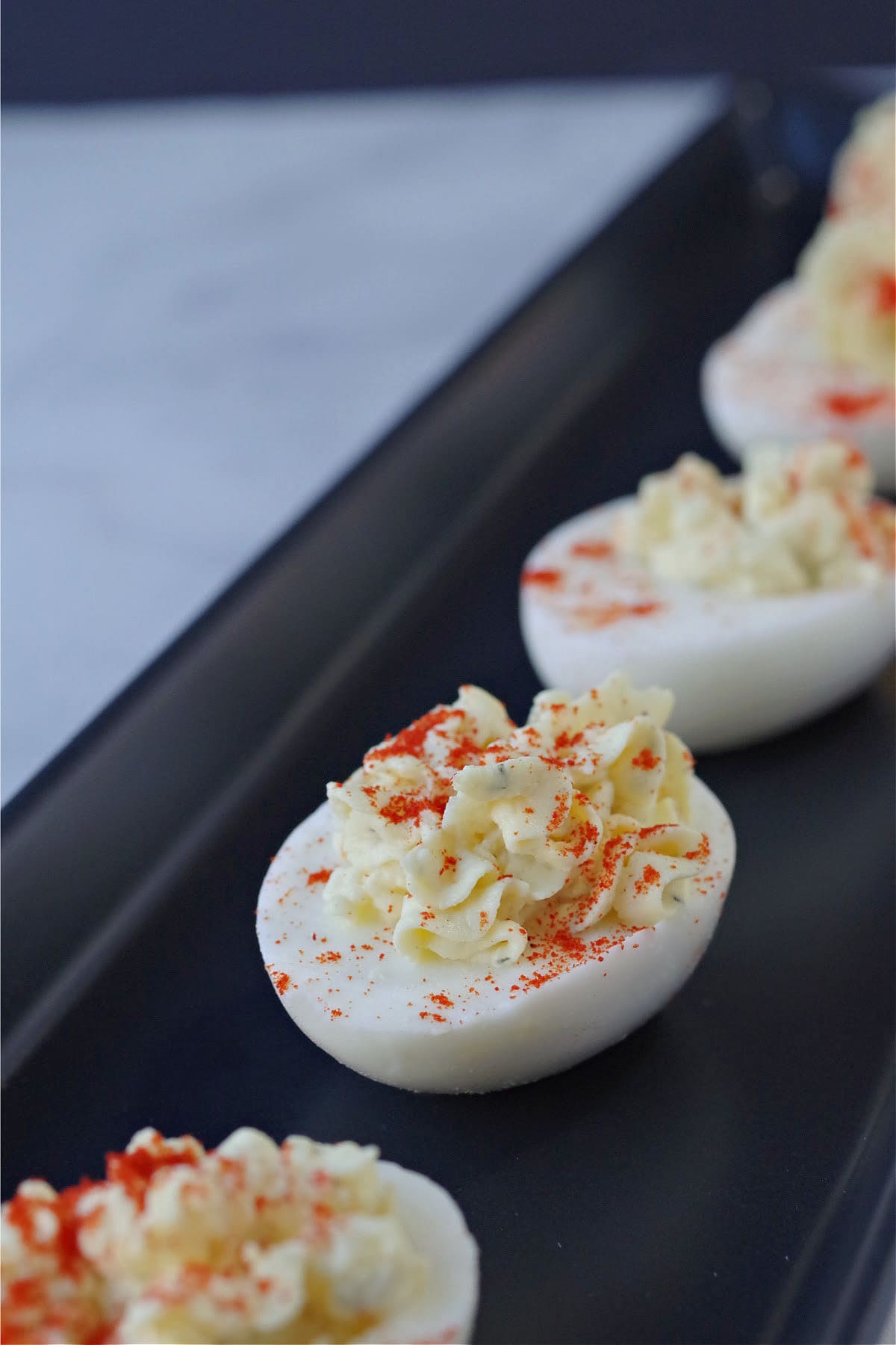 deviled egg with paprika sprinkled on top on black serving tray