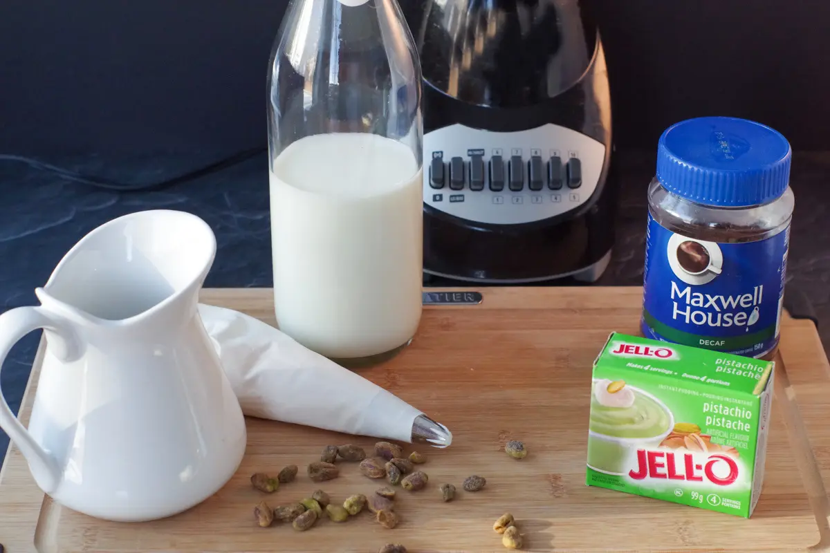 ingredients for pistachio frappuccino on cutting board with blender in background
