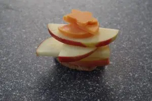 cheese shapes added to apple slices on a grey cutting board