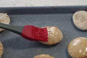 melted butter being spread on a mini pita with a pastry brush