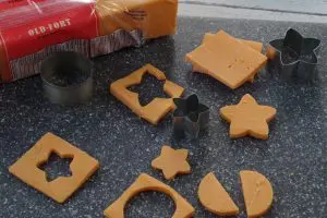 cheese cut outs with mini cookie cutters on a grey cutting board