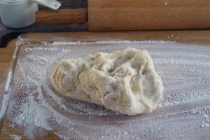 dough on lightly floured surface with rolling pin in background