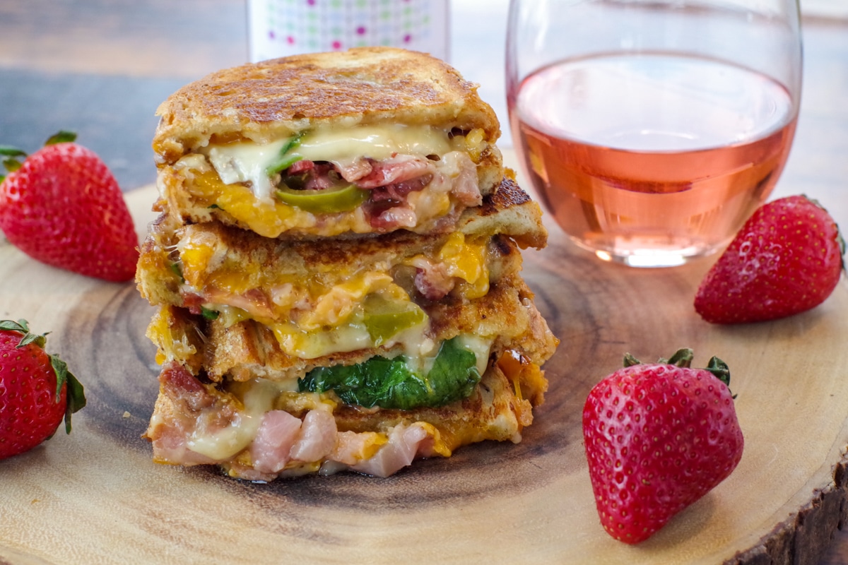 Strawberry Moscato grilled cheese on wooden tree platter with glass of moscato in background and strawberries