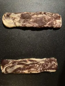 dough shaped into logs on black cutting board