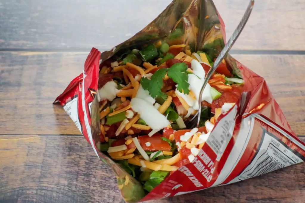 tacos in a bag with fork, on wooden surface
