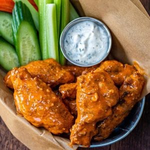 chicken wings in a basket with veggies and dip