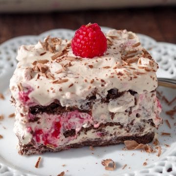 raspberry dulce de leche icebox cake on white plate with glass dish of cake in the background