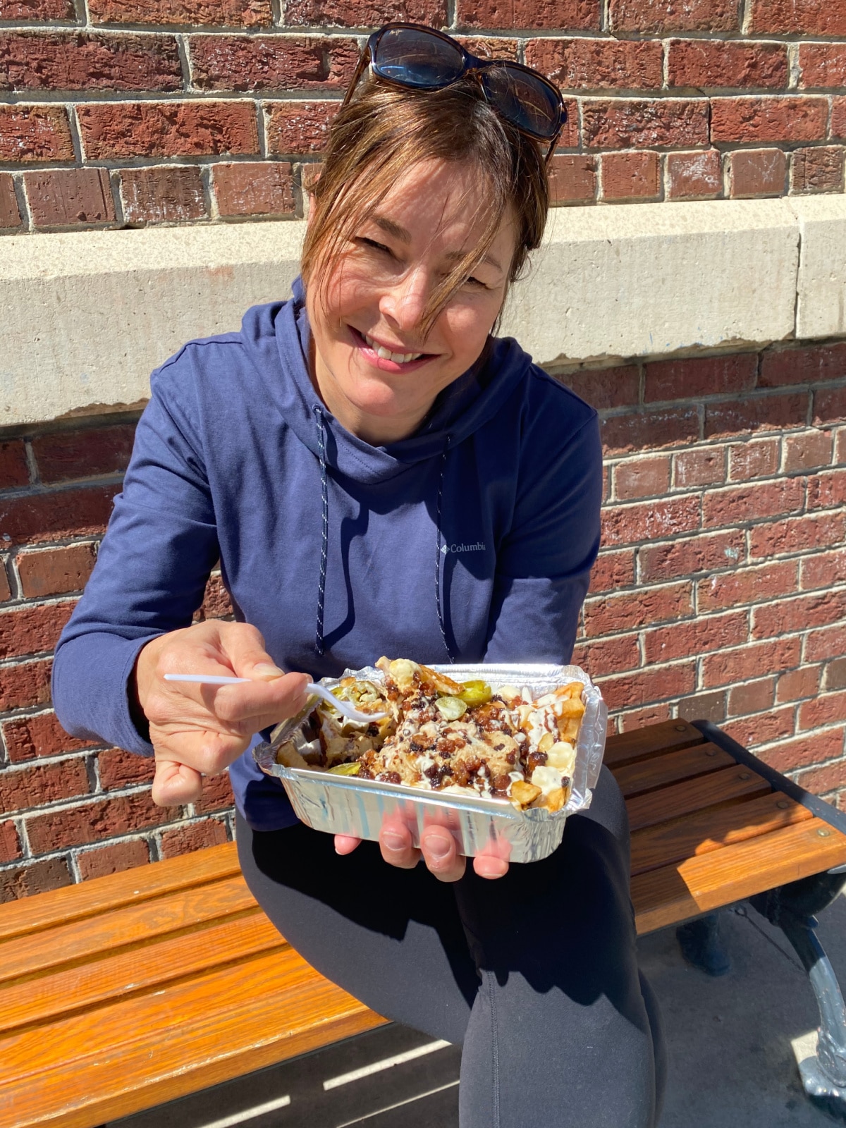 me sitting on a bench eating poutine