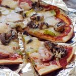 camping pizza on foil, with a slice removed