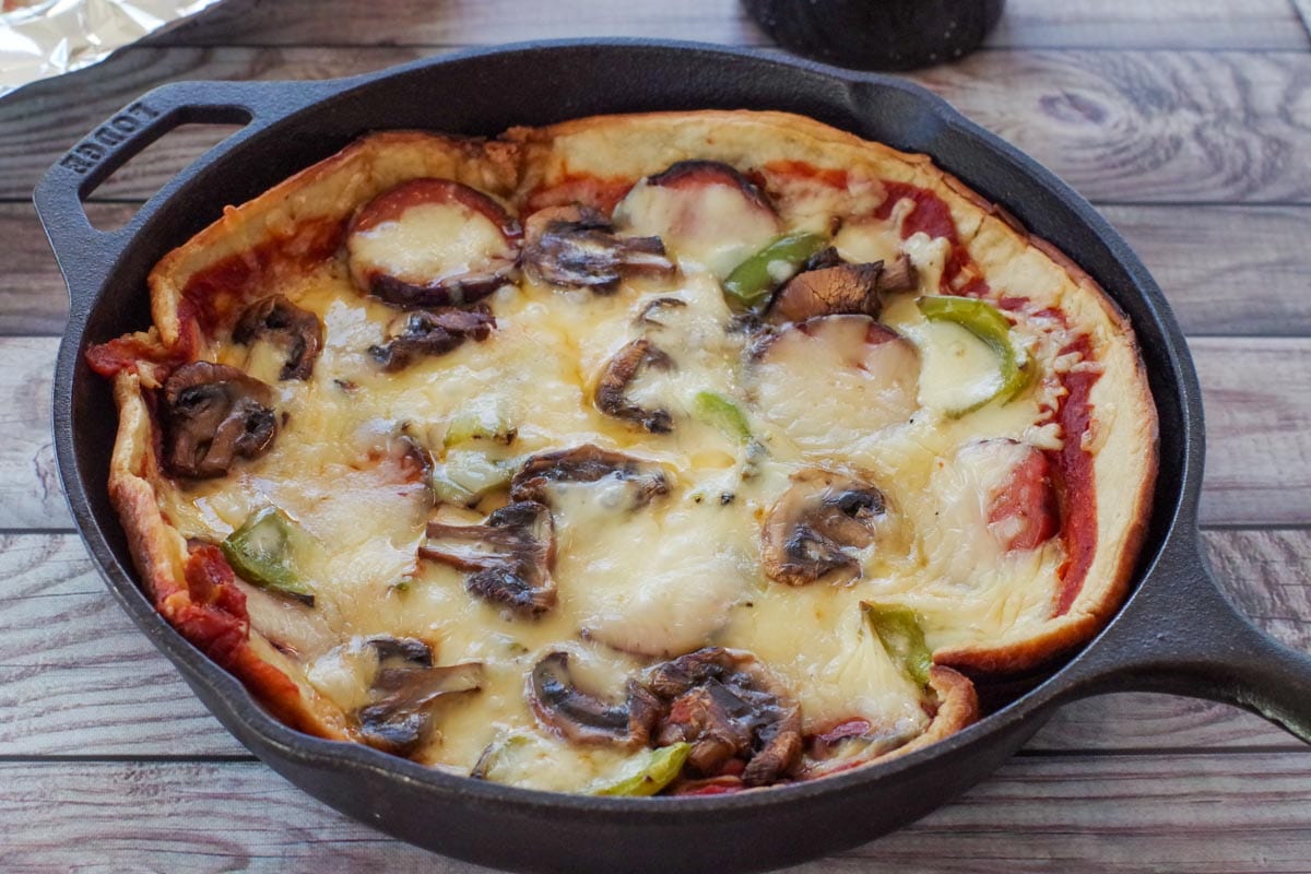 camping pizza with grilled toppings in a cast iron pan