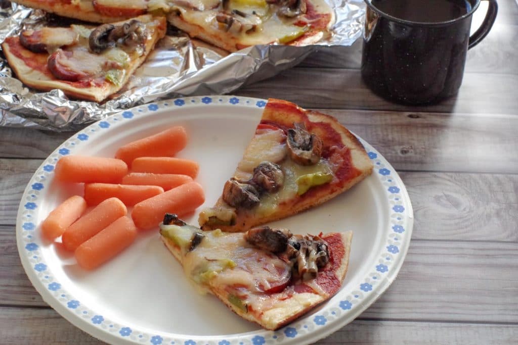 campfire pizza on paper plate with carrots on the side