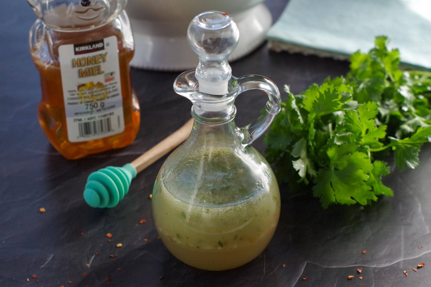bottle of honey lime cilantro dressing with bottle of honey and fresh cilantro