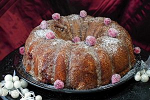 whole cranberry sour cream coffee cake with candied cranberries on a plate