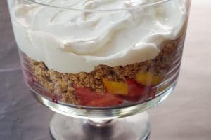 granola and yogurt layered over fruit in trifle bowl