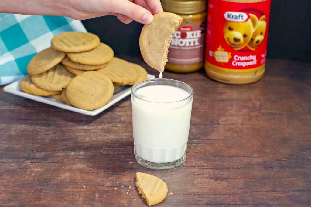 cookie butter cookie being dipped into a glass of milk