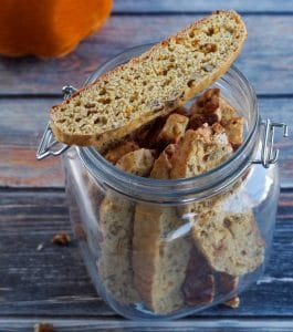 baked and cooled biscotti in jar, with a piece of biscotti on top