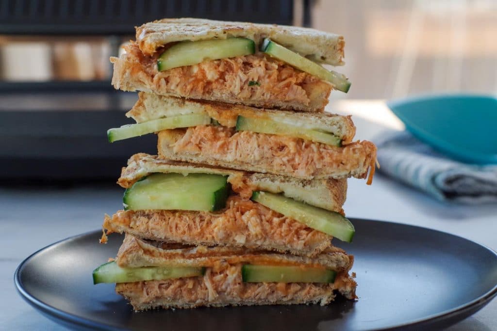 buffalo chicken panini on a black plate with panini press in background