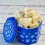 Microwave sugar cookie fudge in blue cookie tin on white faux wood surface