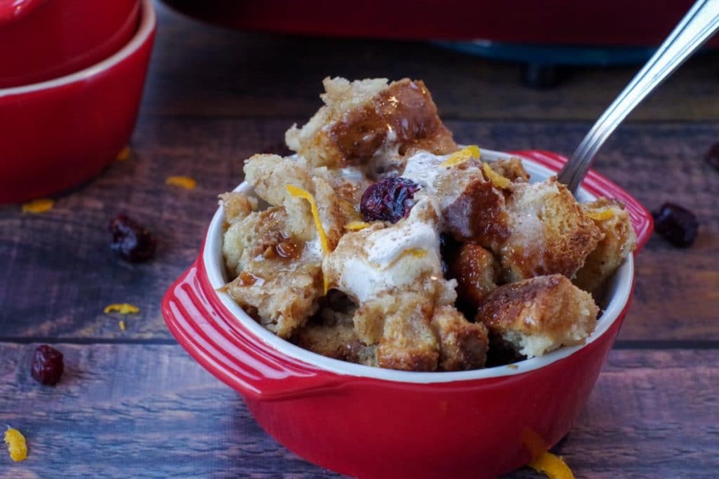 cranberry toffee bread pudding in a red bowl with a spoon