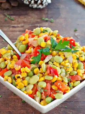 healthy corn succostash in a white bowl on brown wooden surface
