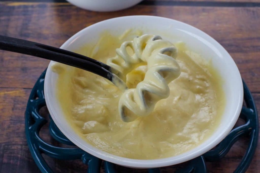 Hollandaise sauce in a white bowl with a whisk