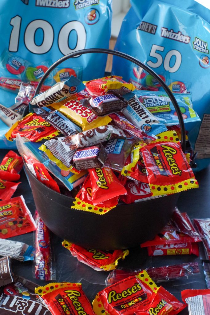 Leftover Halloween Candy in a black plastic cauldron with bags of candy in the background