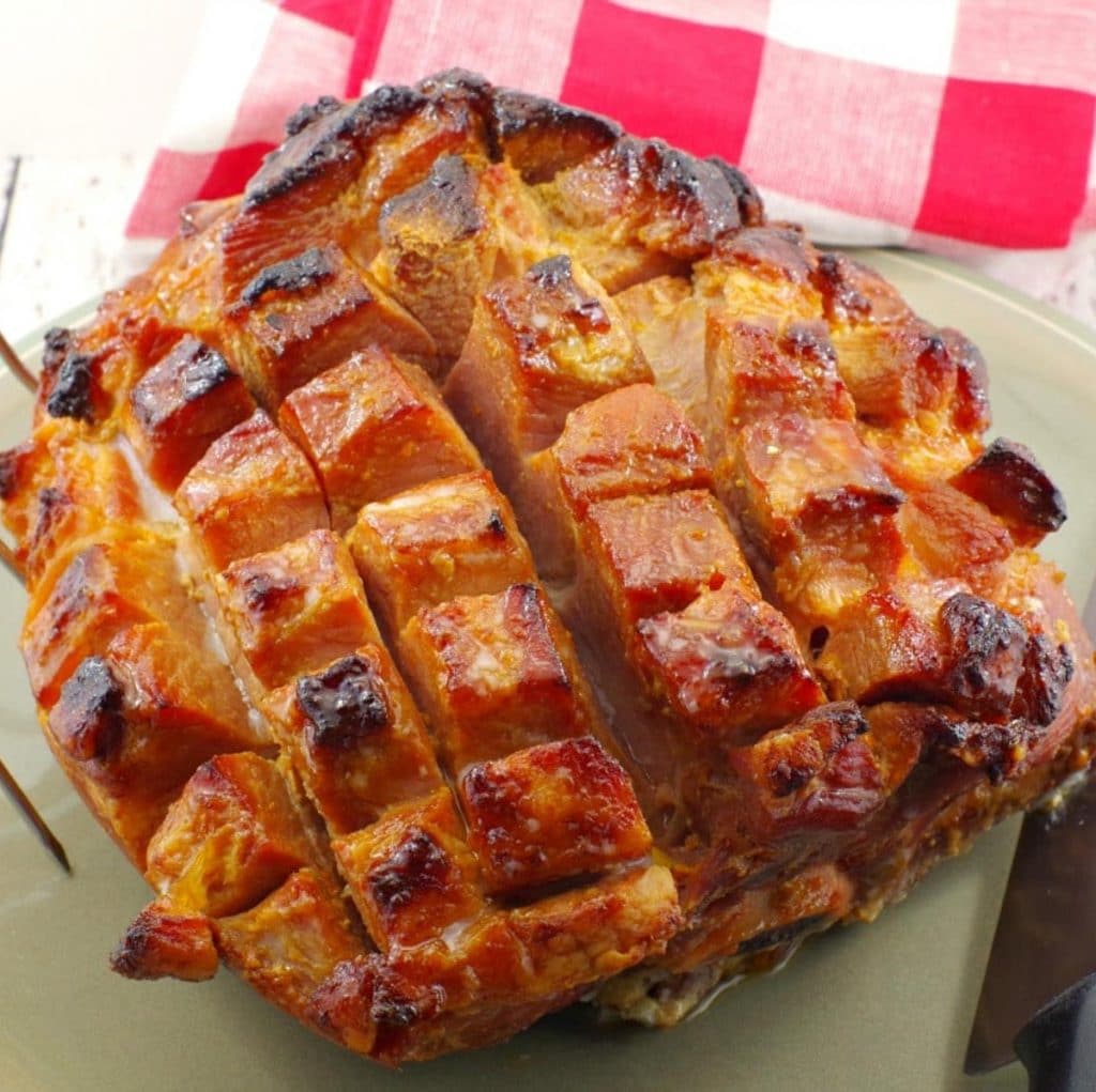 Whole, scored and cooked picnic ham on a plate