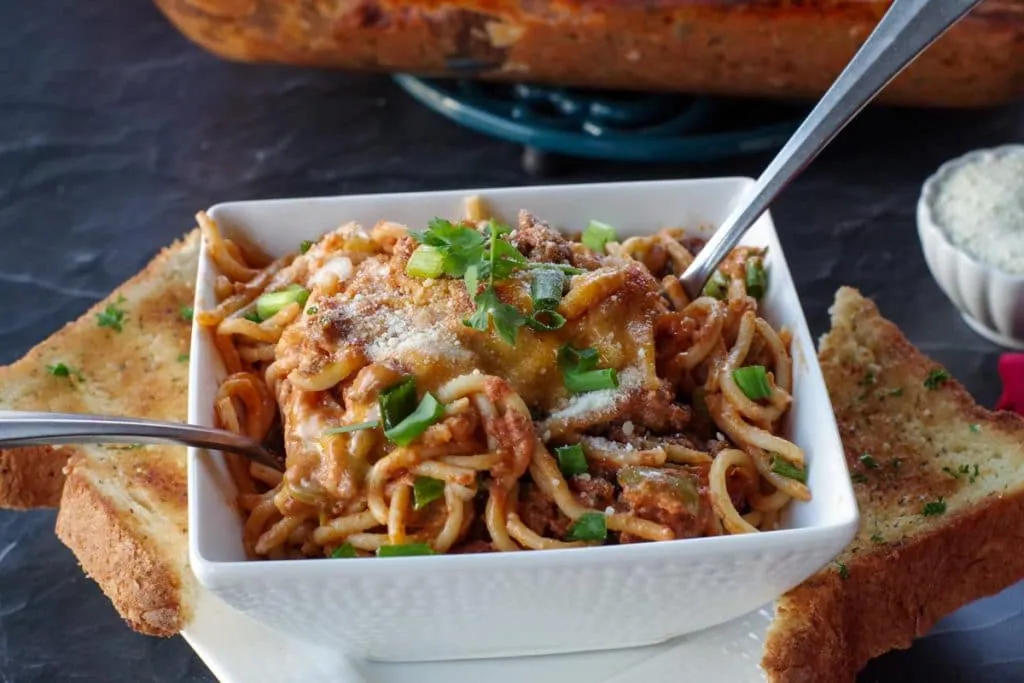 Weight Watchers Spaghetti Casserole in a white bowl with spoon and garlic toast on the side