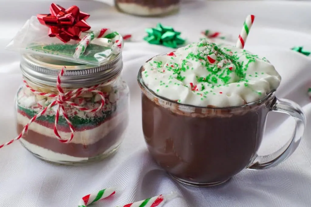 candy cane hot chocolate mix in a jar with a mug of hot chocolate beside it