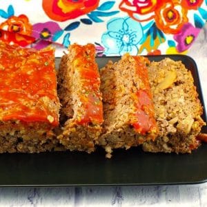 meatloaf, sliced on a black tray with a colorful flower tea towel in the background
