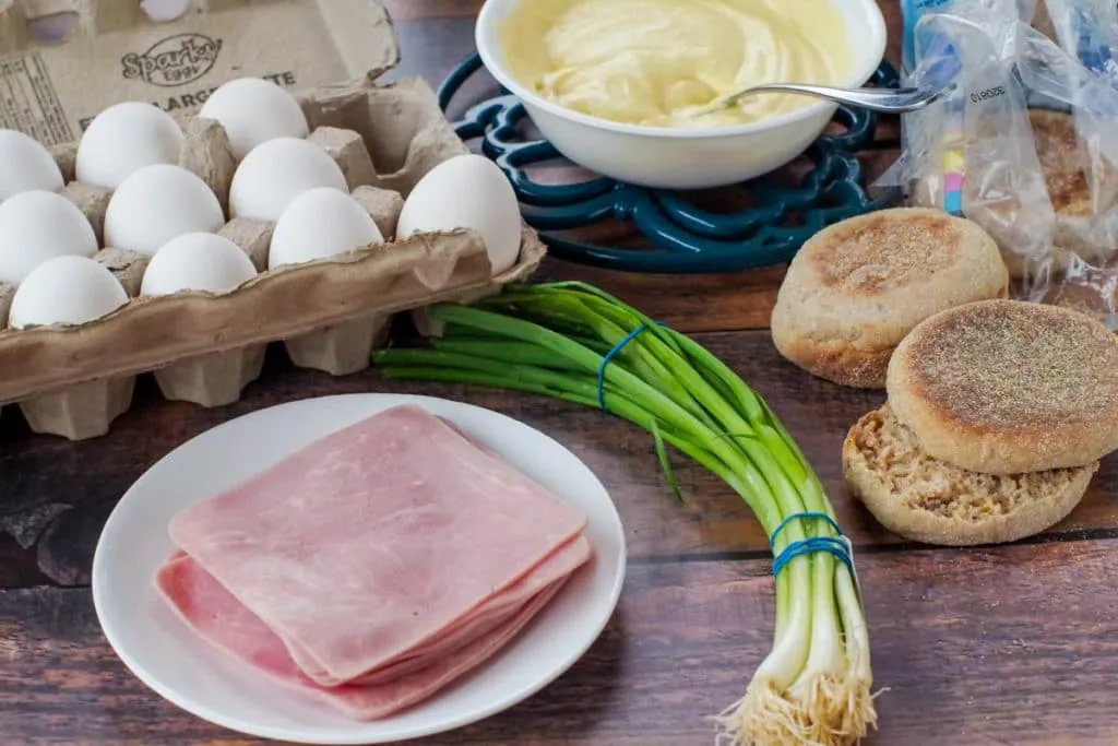 ham, green onion, English muffins, a carton of eggs and a bowl of hollandaise sauce