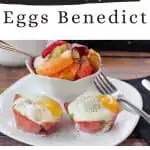 2 healthy eggs benedict on a white plate with a fork and a bowl of fruit