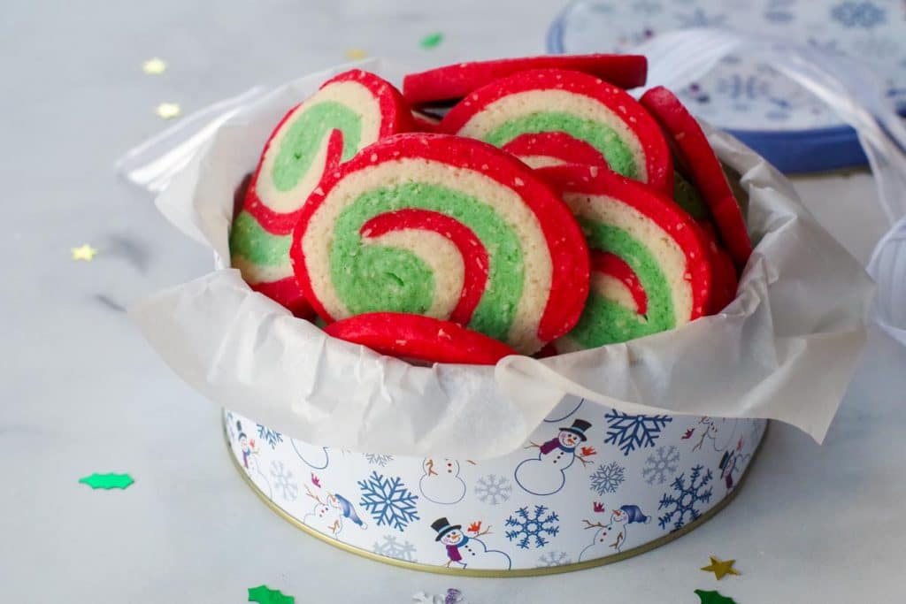 Pinwheel Christmas cookies in a white and blue snowflake patterned cookie tin