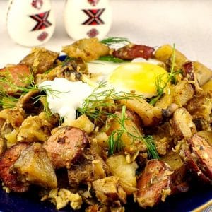 Ukrainian Breakfast Hash on a blue plate, with an egg on top and Ukrainian egg shaped shakers in the background