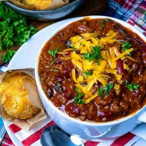 Southern Soul Chili, with cheese and green onion on top, in a white bowl with bread on the side