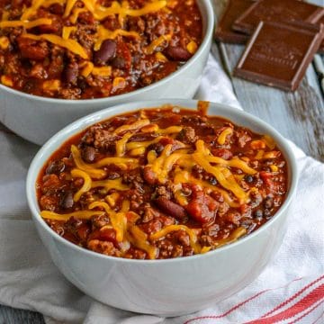 2 bowls of Dad's secret ingredient chili with squares of chocolate in the background