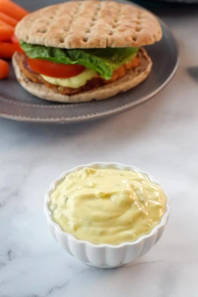 Tartar sauce in a small white dish, with a tuna burger in the background