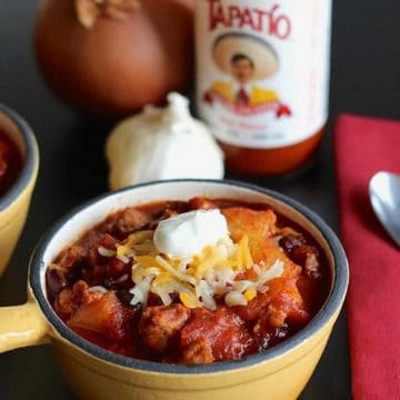 Pineapple chili in a yellow bowl with chili ingredients in the background