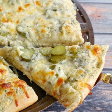 pickle pizza on pan being removed with pizza lifter