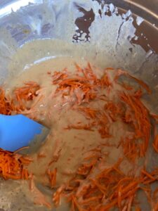 wet ingredients mixed with carrots in a bowl
