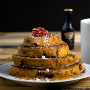 Baileys french toast on a white plate with a bottle of baileys in the background
