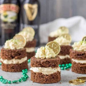 chocolate guinness mini cakes with baileys buttercream and bottles of baileys and guinness in the background