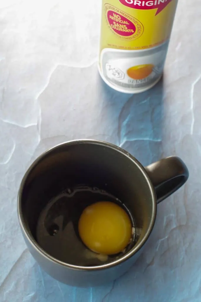 egg in a mug with non-stick cooking spray in background