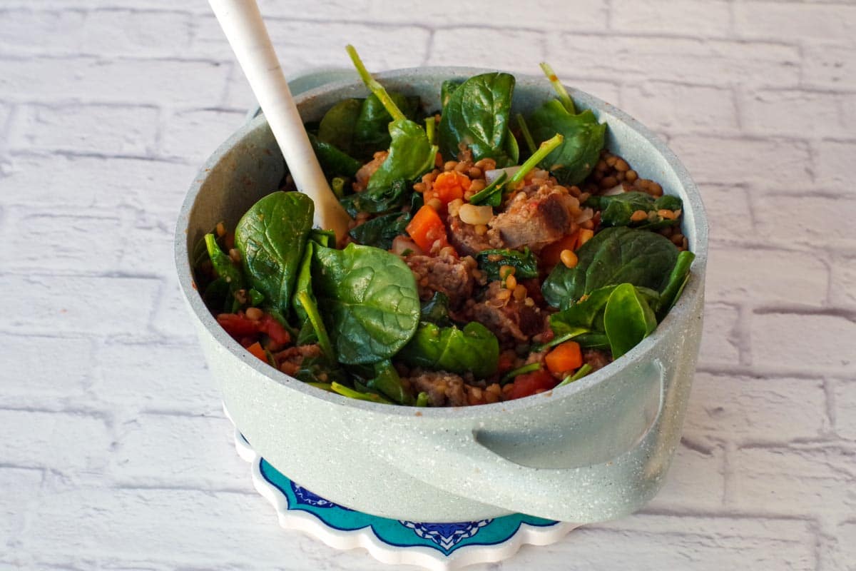 spinach being added to stew in batches