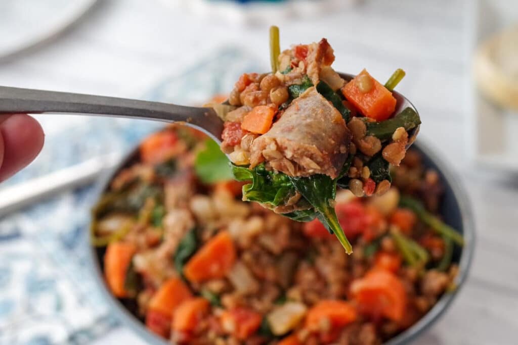 Lentil and Sausage stew (with spinach) being held up on a spoon)
