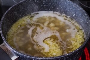 beef stock boiling on stove with onions and butter